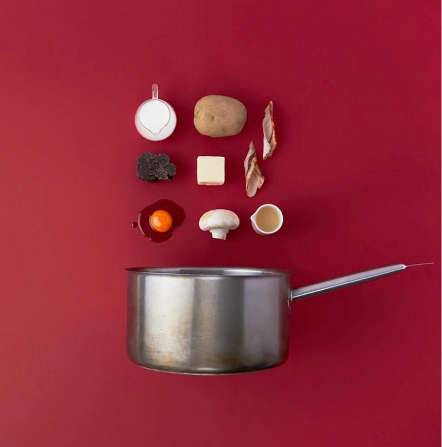 Ingredientes y una cazuela sobre fondo rojo
